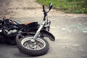 A crashed motorcycle next to broken glass, where the owner will need a Motorcycle Accident Attorney in Peoria IL