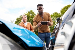 A man taking pictures of a car collision for his Auto Accident Lawyer in Peoria IL